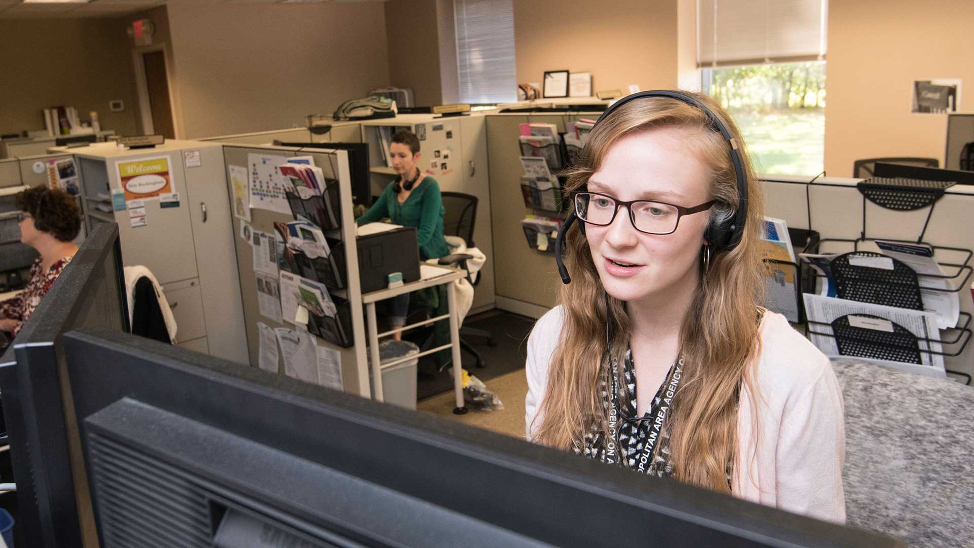 Photo of a person sitting at a desk wearing a headset.