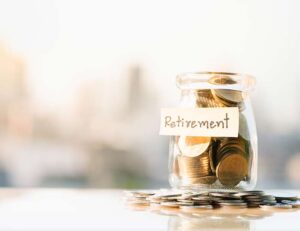 Photo of a jar filled with coins. A sticky note on the jar reads "retirement."