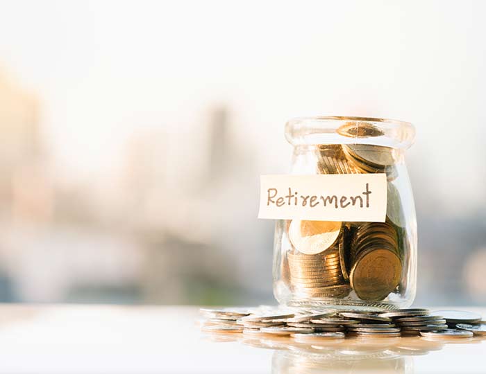 Photo of a jar filled with coins. A sticky note on the jar reads "retirement."