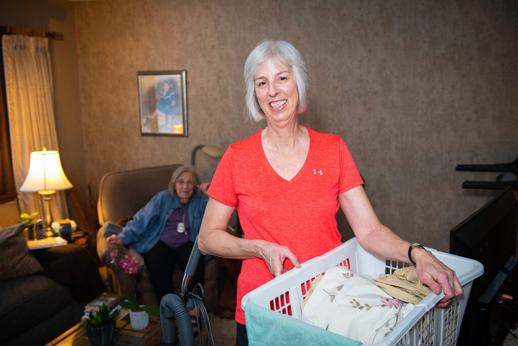 Photo of a woman carrying a hamper full of laundry.