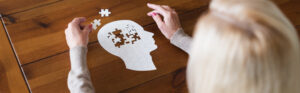 Photo of a person putting a puzzle together that is shaped like a human head.