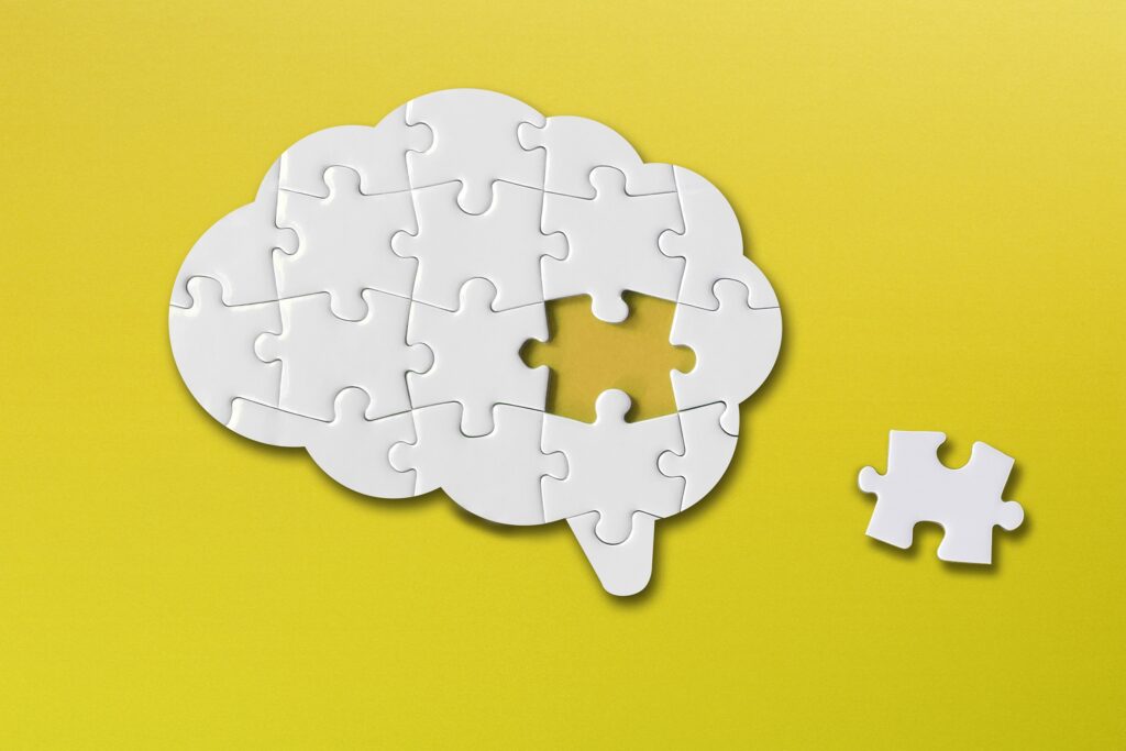 Image of a puzzle shaped like a brain. The puzzle is complete except for one piece laying to the side.