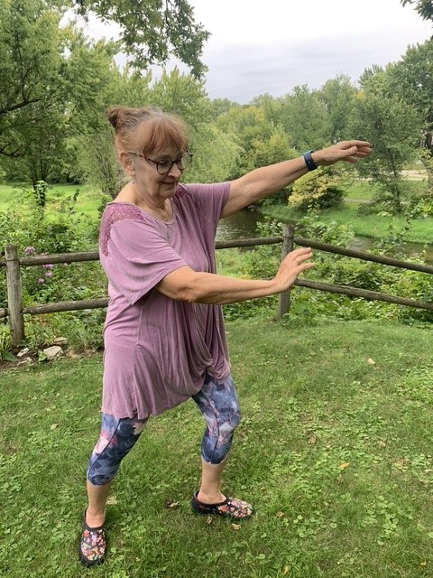 A woman practicing tai chi outdoors.