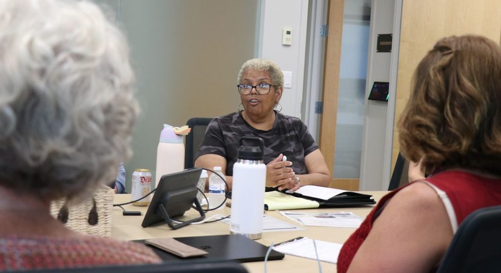 Photo of a woman speaking during a meeting in a conference room.