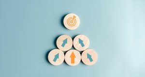 Five wooden tokens with arrows on them pointing toward a wooden token with a target icon.