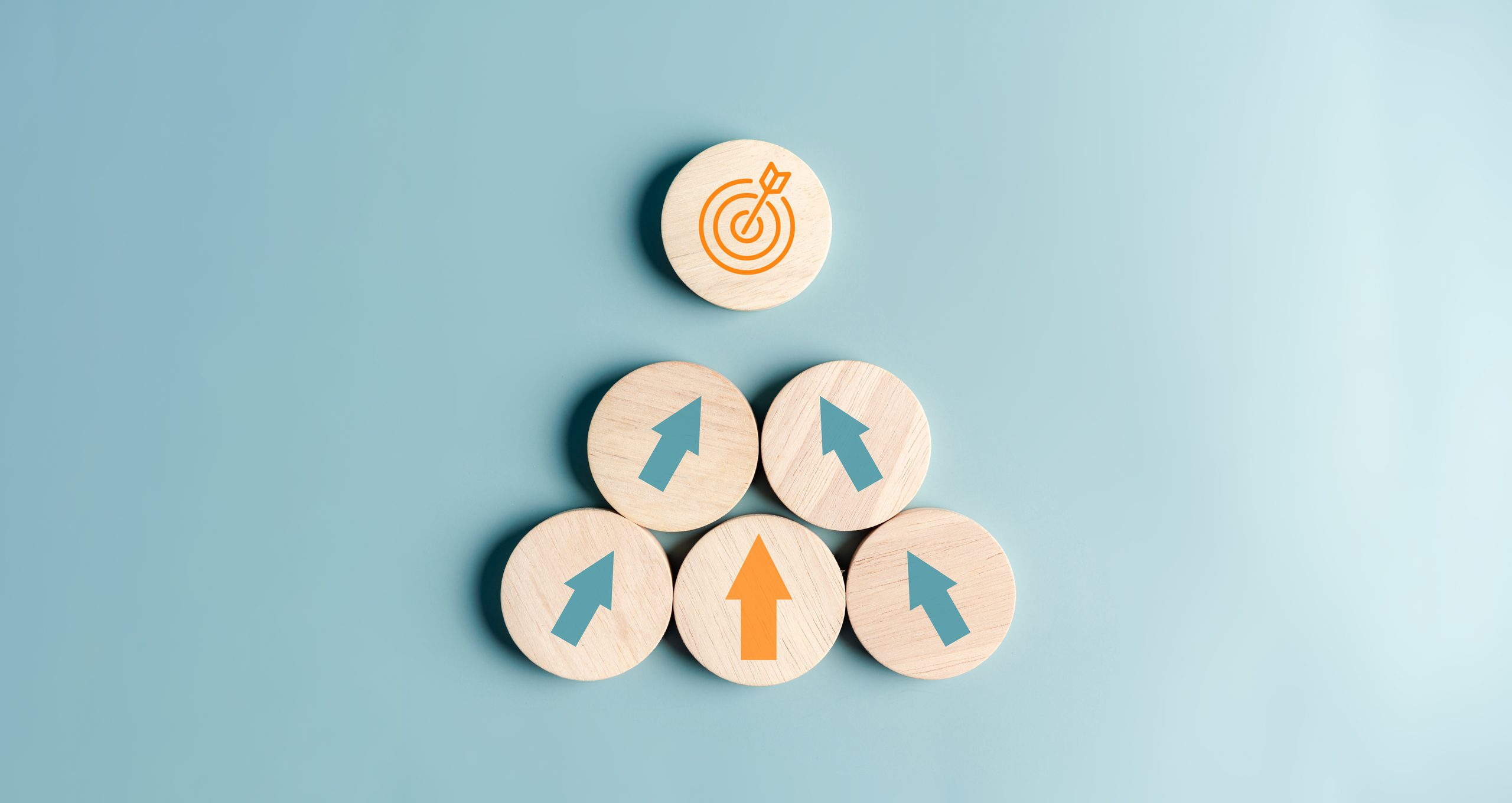 Five wooden tokens with arrows on them pointing toward a wooden token with a target icon.