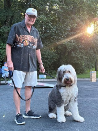Photo of Kale posing with his dog outdoors.